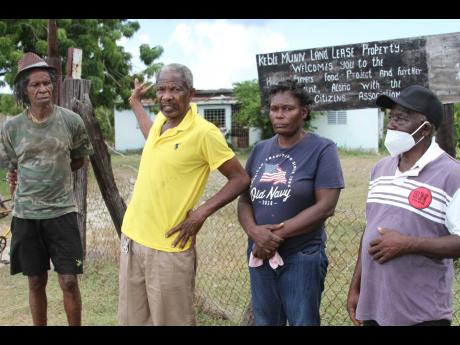 Carlton Campbell (second left), of Project Land Lease, Raymonds Clarendon explains the terms of a lease agreement signed in the 1970s between residents and then Minister of Agriculture Keble Munn, to lease over 700 acres of land to 220 farmers for 49 years