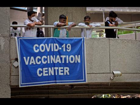 People watch others arrive to receive the COVID-19 vaccine at a government-run hospital in New Delhi, India, on Tuesday.