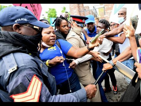 Fellow protesters try to stop the police from detaining this young man as they marched towards Gordon House in protest against what they believe is an impending move by the Government to make the COVID-19 jab mandatory.