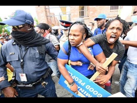 Police detain a protester during an unauthorised march in downtown Kingston yesterday.