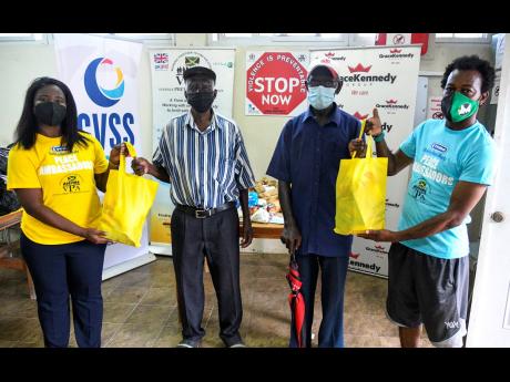 Jonelle Llewellyn (left), research associate at the Violence Prevention Alliance, presents care packages to Julius Roye (second left), Leroy Thompson (second right) and O’Neal Beaver, residents of Cassava Piece. The donation of the care packages was one 