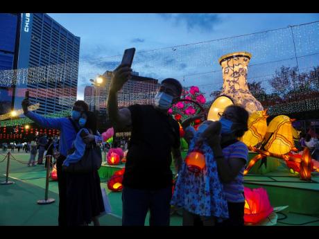 People take selfies in front of glowing lanterns during the Mid-Autumn Festival at Victoria Park in Hong Kong.