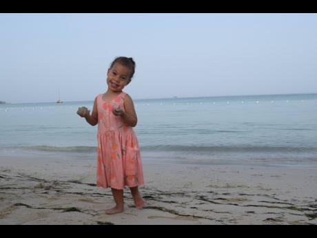 Little Morgana Melvin enjoys an early morning playing on the white sand beach of the Charela Inn. 