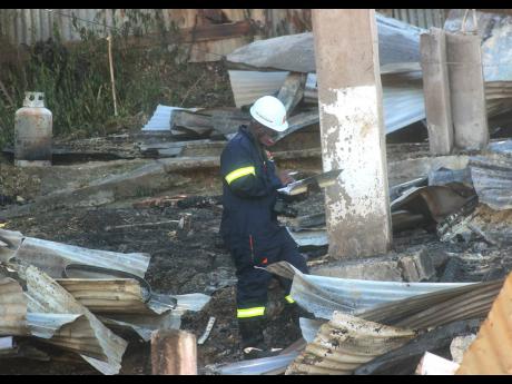 A firefighter makes recordings in a logbook at an arson scene in Granville, St James, on Sunday.