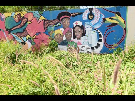 A mural in a neglected section of Rockfort overgrown with shrubs in east Kingston.