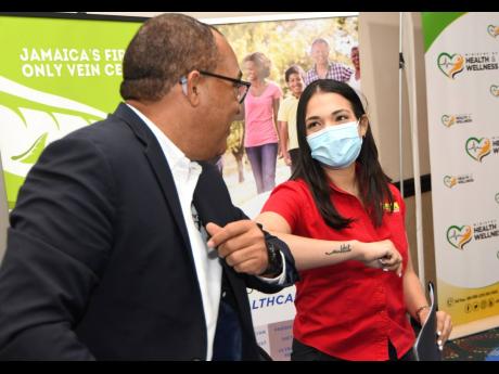 Dr Christopher Tufton, minister of health and wellness, playfully elbow-greets Alanah Jones, special projects manager of Fontana Pharmacy, after inking an agreement under which the ministry will engage private interests in administering COVID-19 vaccines.