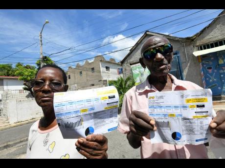 Valerie Grant and Rudolph Campbell, residents of Woodford Park, show electricity bills issued by the Jamaica Public Service Company. They said that consistent outages in the southeast St Andrew community have caused spoilage of meat and other inconvenience