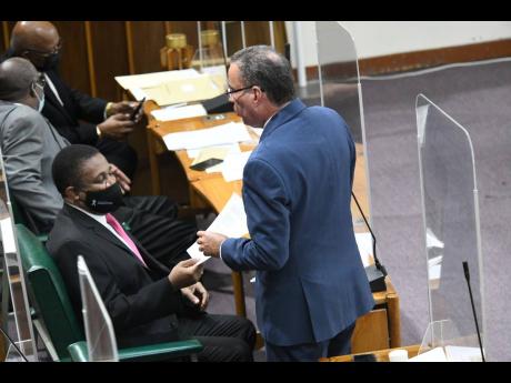 Daryl Vaz (right), minister of energy, science and technology, talks to Phillip Paulwell, member of parliament for Kingston Eastern and Port Royal, before delivering a statement to lawmakers at Tuesday’s sitting of the House of Representatives. Vaz and P