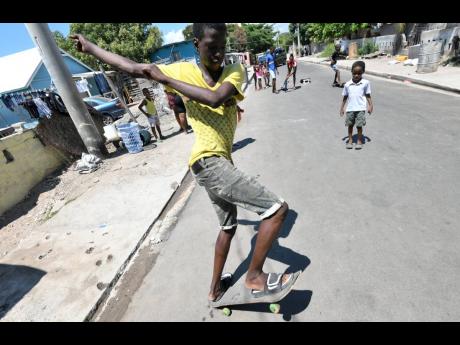 Youngsters showing off their skateboarding skills on Second Street in Trench Town, St Andrew, yesterday. 