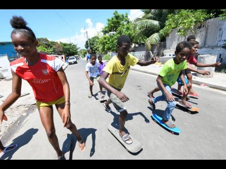 Youngsters display their skateboarding skills on Second Street in Trench Town, St Andrew, on Wednesday. Scores of children were given skateboards in June by a volunteer at Boys’ Town who has often sought to have students involved in extracurricular activ