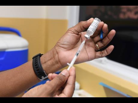 Public-health nurse Jasmin Thomas fills a syringe with the AstraZeneca COVID-19 vaccine as she prepares to administer a dose at the University Hospital of the West Indies on Thursday. More than 50,000 doses of AstraZeneca gifted by the United Kingdom are e
