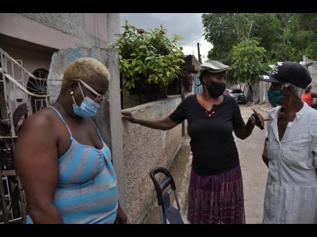 Ian Allen/Photographer 
Friends of Beryl Bryan reflect amid grief at her gate in Drewsland, St Andrew, yesterday. Bryant’s body was recovered yesterday after she was washed away in a gully on Thursday.