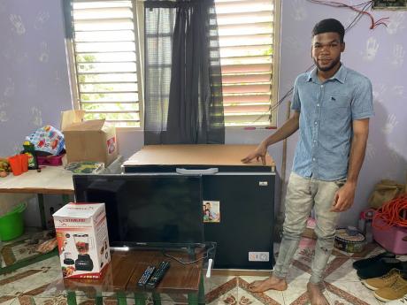 Michael Reid standing beside a new freezer, television set and blender he bought with funds recently donated to him.  