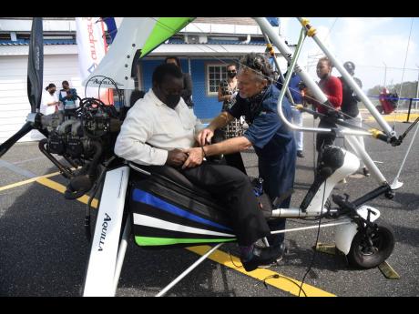David Daniels (right), chief pilot and engineer of Amber Aviation, straps in Robert Montaque, minister of transport and mining, for a flight in the microlight aircraft at the Ian Fleming International Airport in Boscobel, St Mary, on Friday.  