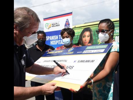 
Jean-Philippe Beyer (left), managing director of J. Wray & Nephew Jamaica and the Caribbean, signs the symbolic cheque of $5 million during a ceremony to mark the donation to the Spanish Town Hospital on October 7.  Witnessing the signing are Tanikie McCl