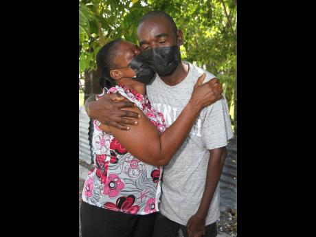 Amoy Johnson (right), of York Town, Clarendon gets a hug and a kiss from his mother, Sandra McDonald-Currie after his act of honesty was recognised at his home on Monday, October 11.