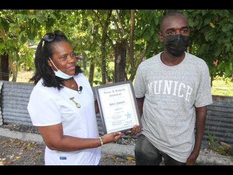 Amoy Johnson (right), of York Town, Clarendon, receives a certificate from Faustina Richards for his act of honesty.