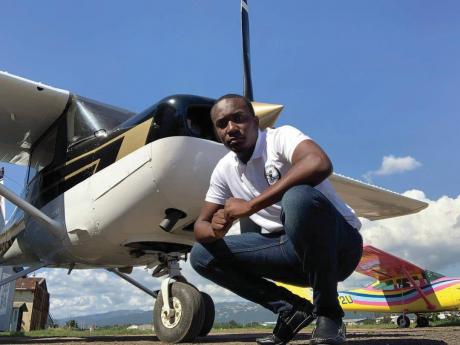 Aspiring pilot Rohan Ellis stoops in front of the Cessna aircraft on which he is learning to fly at the Aeronautical School of the West Indies, which is located at the Tinson Pen Aerodrome, Kingston. 