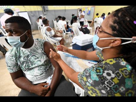 Rochell Rochester-Kerr, registered midwife, administers the first dose of COVID-19 vaccine to Romell Samon at an inoculation drive in Ewarton, St Catherine, on Sunday, October 3. 