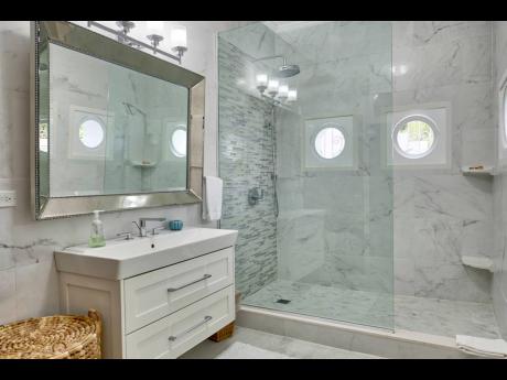 The bathroom with its partly glass enclosed shower and porthole ship windows.