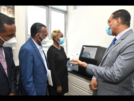
Prime Minister Andrew Holness (right), looks at the genome sequencer machine with (from left) Dr Carl Bruce, medical chief of staff and consultant neurosurgeon of The University Hospital of the West Indies (UHWI); W. Billy Heaven, CEO, CHASE Fund; and Jul