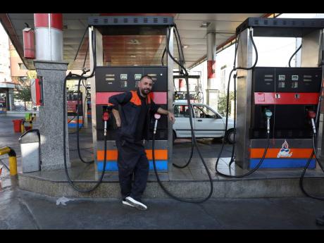 A worker leans against a gasoline pump that has been turned off, at a gas station in Tehran, Iran, yesterday. Gas stations across Iran on Tuesday suffered through a widespread outage of a system that allows consumers to buy fuel with a government-issued ca