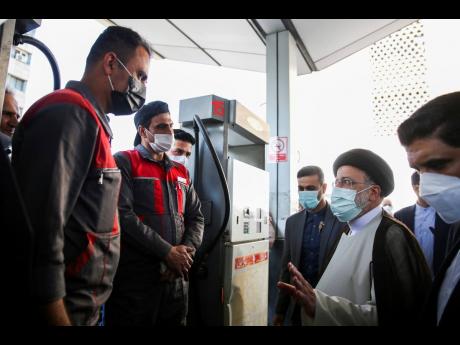 Iranian President Ebrahim Raisi (second right) speaks with gas station workers in Tehran, Iran, yesterday. Raisi said that a cyberattack which paralysed every gas station in the Islamic Republic was designed to get “people angry by creating disorder and 