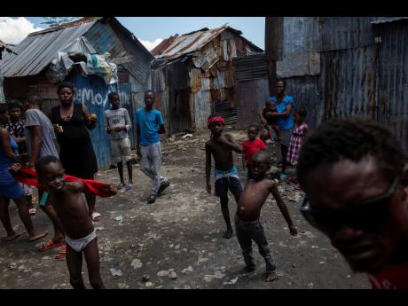 Neighbours gather outside their homes built with recycled metal sheets in the Bellecour-Cite Soleil shanty town of Port-au-Prince, Haiti. Bellecour-Cité Soleil, a neighbourhood of tin shacks without water, electricity or any basic services, is the strongh