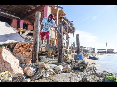 Kingsley Johnson, owner of Any Money One Stop on Hellshire Beach, has watched as shoreline erosion eats away at the sand.