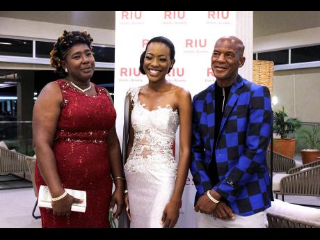 Top five finalist and winner of the sectional award for Best In Evening Wear, Kim-Marie Spence, is cloaked in the warmth of her mother, Avis Walker (left) and father Narcis Spence. 