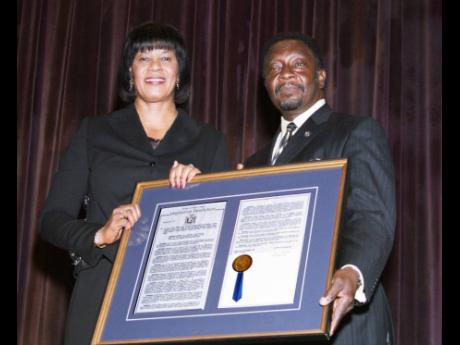 Jamaica-born New York State Assemblyman Nick Perry presents a proclamation to then Jamaica Prime Minister Portia Simpson Miller recognising her as a trailblazing politician and for her dedication to public service. The proclamation was presented at a town 