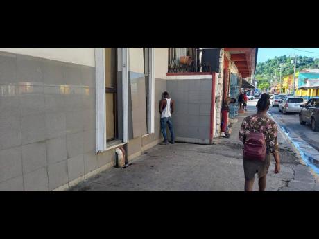 A man of unsound mind is seen urinating along the corridor and walkway of a commercial bank in Port Antonio, hours after that area was washed and sanitised.