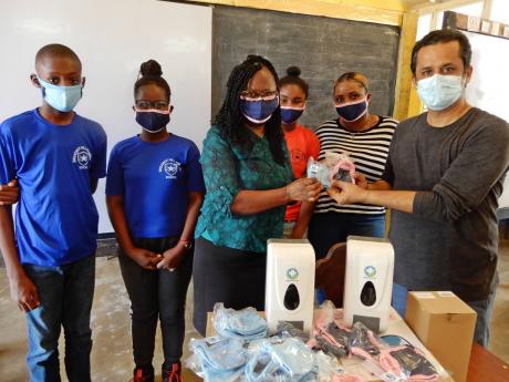 Sherron Minott, principal of Breadnut Hill Primary School, accepts the donation of masks and soap dispensers from Larry Thakurani, who handed them over on behalf of his daughter, Kashish Thakurani of Hillel Academy. 
