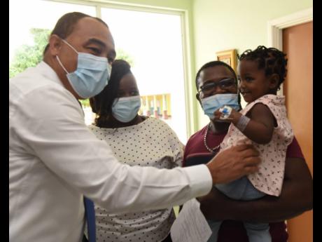 Health and Wellness Minister Dr Christopher Tufton plays with 16-month-old Charlotte Facey during a visit to the Bustamante Hospital for Children on Wednesday. Looking on is Charlotte’s father, Shermott Facey, and her mother, Tianne Smith. Charlotte was 