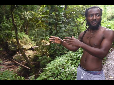Sandrae Walker, a resident of Ham Walk, St Catherine North Eastern, shows the boulders that block the free flow of the  Ital River, which causes flooding in the district during heavy rains.