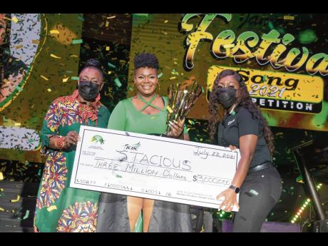 Minister of Culture, Gender, Entertainment and Sport Olivia ‘Babsy’ Grange (left), and Digicel Brand Marketing Manager Reshima Kelly-Williams (right) hands over the grand prize of $3 million to an overjoyed Stacious, winner of the 2021 Jamaica Festival