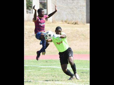 Camperdown High School’s goalkeeper, Alphanso Claken (right), catches the ball ahead of Omar Laing (left) from St. Andrew Technical High School (STATHS) during their ISSA Manning Cup football match at the Stadium East playing field yesterday. Camperdown 