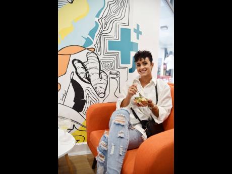 Artist Simone Raquel Williams was ready to nosh on a delectable bite while seated next to her mural at the Jamaica Food & Drink Kitchen. 