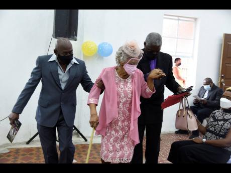 Carlton Kelly (left) and Pastor Phillip Smith assist Joyce Gray, a veteran educator, to her seat. Gray, who retired in 2008, taught for 56 years. An appreciation service for her was held at Church of God of Prophecy, Mount Salus Road. 
