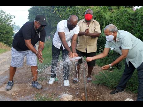 Pearnel Charles Jr (second left), MP for Clarendon South East, and Councillor Winston Maragh (right), mayor of May Pen, celebrated with Jerome Lofters (left) and Neville Reid on Saturday as piped water flowed to homes in Salt River for the first time in de