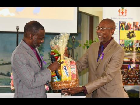 Denzil Thorpe (left), permanent secretary in the Ministry of Culture, Gender, Entertainment and Sport, presents a gift basket to the pastor of the Constant Spring Road Church of God, the Rev George Lewis, following the church service to recognise the Inter