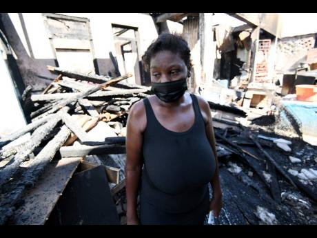 Junisha Campbell is a picture of dejection as she stands amid the rubble of a dwelling on Hanover Street, Kingston, that was razed by fire on Tuesday.