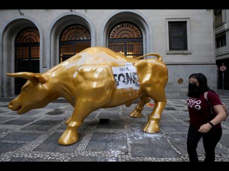 
An activist walks past the Golden Bull, a replica of Wall Street’s Charging Bull symbolising the financial market, after her group pasted the Portuguese word for ‘hungry’ on it, outside the Brazilian B3 Stock Exchange in Sao Paulo on November 17.