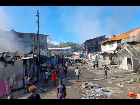 People walk through the looted streets of Chinatown in Honiara, Solomon Islands yesterday. Solomon Islands Prime Minister Manasseh Sogavare on Friday blamed foreign interference over his government’s decision to switch alliances from Taiwan to Beijing fo