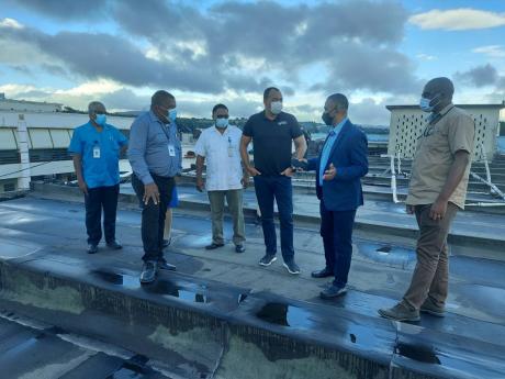 Minister of Health and Wellness Dr Christopher Tufton (third right) examines sections of the repaired roof of the Mandeville Regional Hospital with (from left ) Senior Medical Officer Dr Everton McIntosh, Southern Regional Health Authority Regional Directo