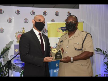 Commissioner of Police Major General Antony Anderson (left) presents the Dr  Marshall Hall Award to St Catherine North Divisional Commander, Superintendent Howard Chambers. The occasion was the 2021 Police Civilian Oversight Authority  Area 4 Transforming 