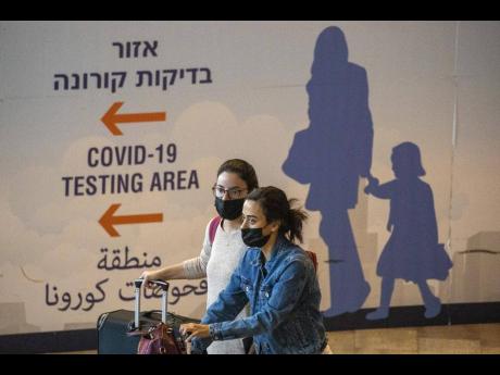 Travellers wearing protective face masks arrive at Ben Gurion Airport near Tel Aviv, Israel, yesterday. Israel on Sunday approved barring entry to foreign nationals and the use of controversial technology for contact tracing as part of its efforts to clamp