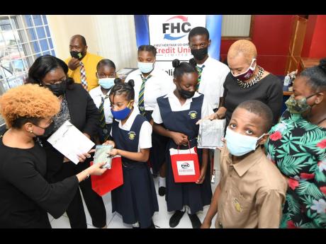 Fayval Williams (second right), minister of education; Trudy-Ann Stewart (second left), manager of First Heritage Co-operative Credit Union’s Kingston Gardens branch; and Michelle Tracey (left), assistant general manager, present tablets to students whil