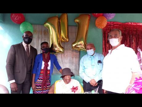 Centenarian and Jamaica’s oldest resident; Louisea McDonald, celebrating her 111th birthday at her home in Bog Hole, Clarendon, on Wednesday, December 1. She is flanked (from left) by Clarendon Northern Member of Parliament Dwight Sibblies; Toshane Young