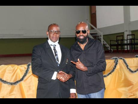 Principal of Tivoli Gardens High School Marvin Johnson (left) and Cleve ‘Lt Stitchie’ Laing, president, Tivoli Gardens High School Alumni Track Corporation, shake hands after they both shared important messages with the school’s students and parents.